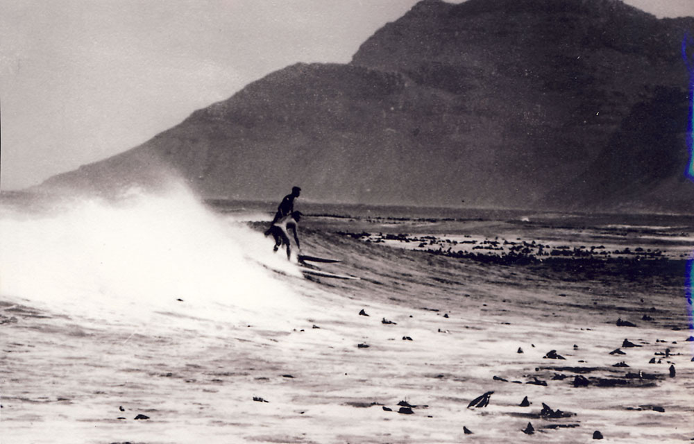 Riding a wave at Kommetjie in the early 1950s with Cape big wave pioneer Dave 'Rockspider' Meneses. Photo copyright Gordon Verhoef.